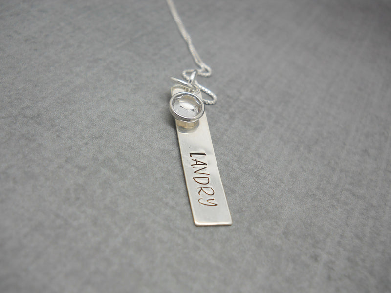 Hand Stamped Bar Name Necklace in Sterling Silver, Margarita font, flat lay