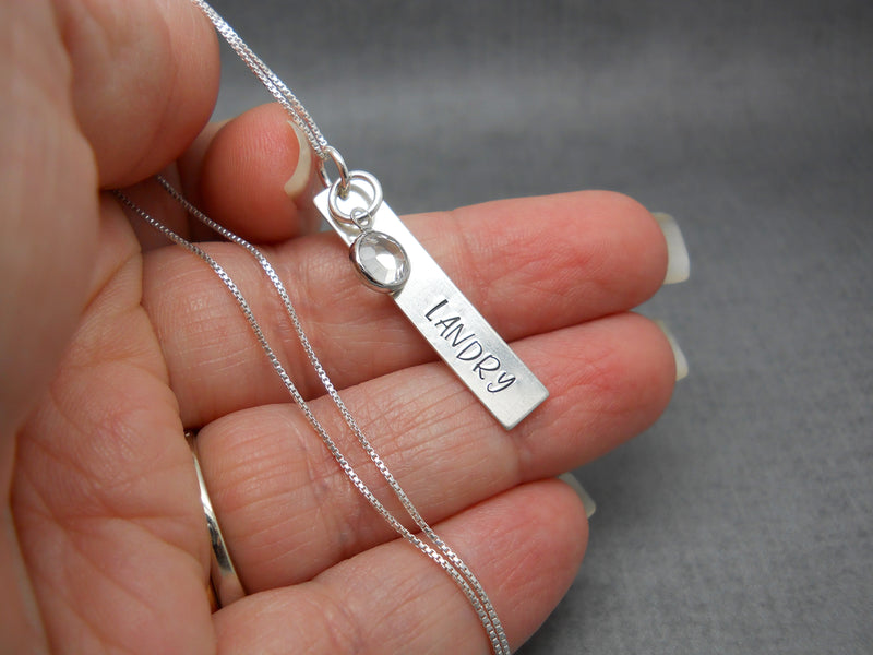 Hand Stamped Bar Name Necklace in Sterling Silver, Margarita font, held in hand